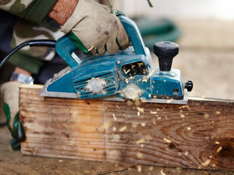 Cepillo eléctrico rebajando una pieza de madera antigua